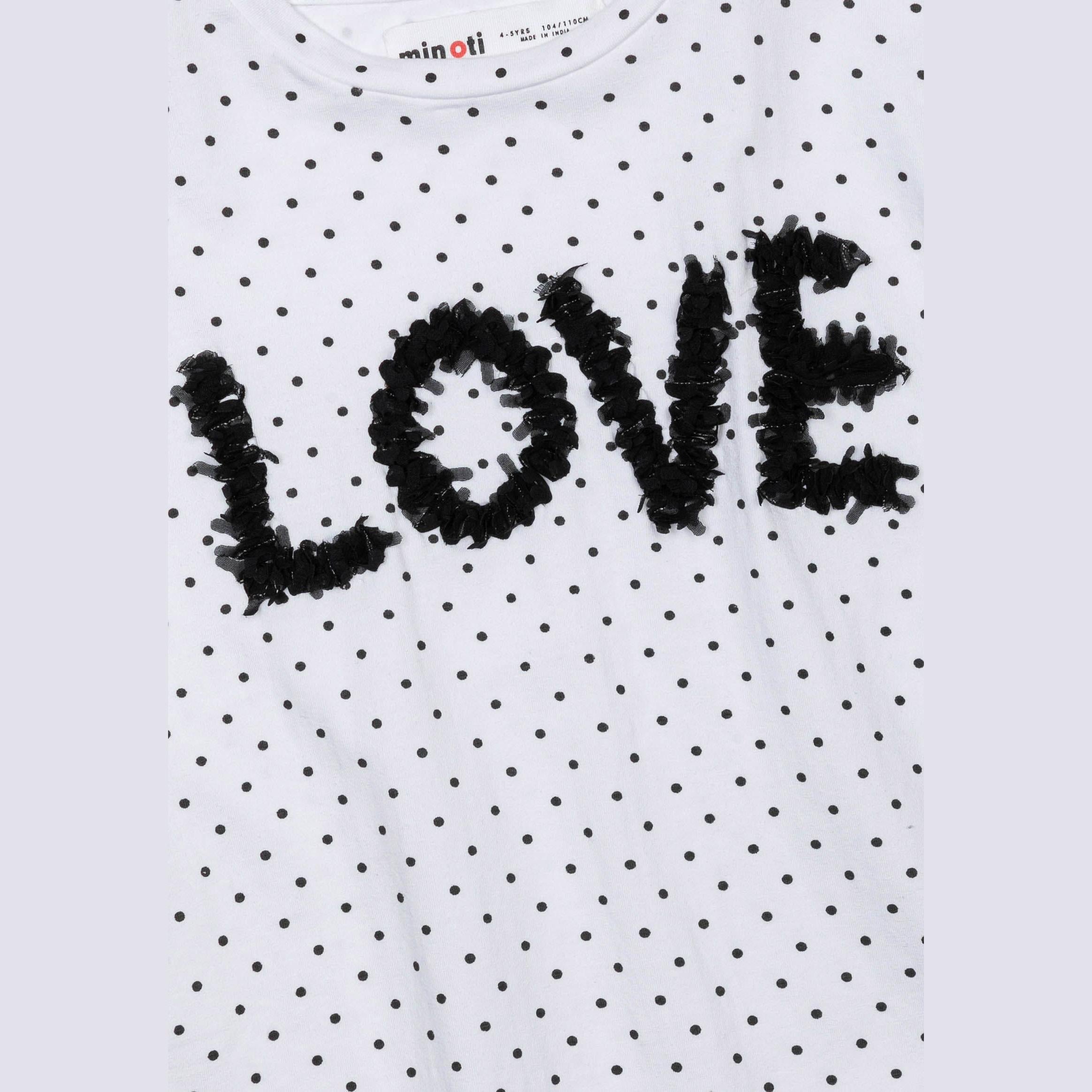 Close-up detail of textured black LOVE applique on white polka dot fabric showing dimensional chiffon lettering