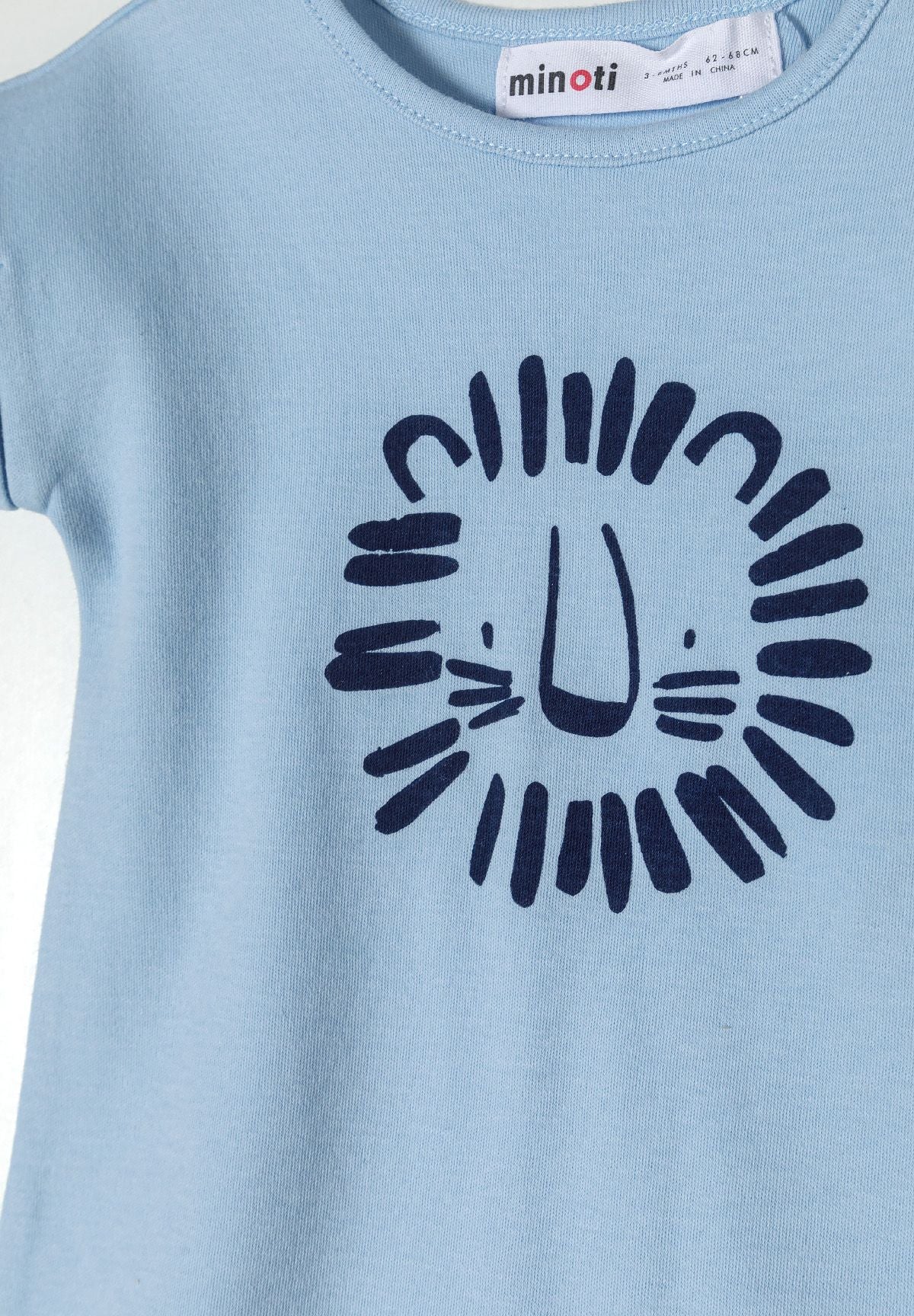 Light blue short sleeve romper with lion print detail, close-up view.