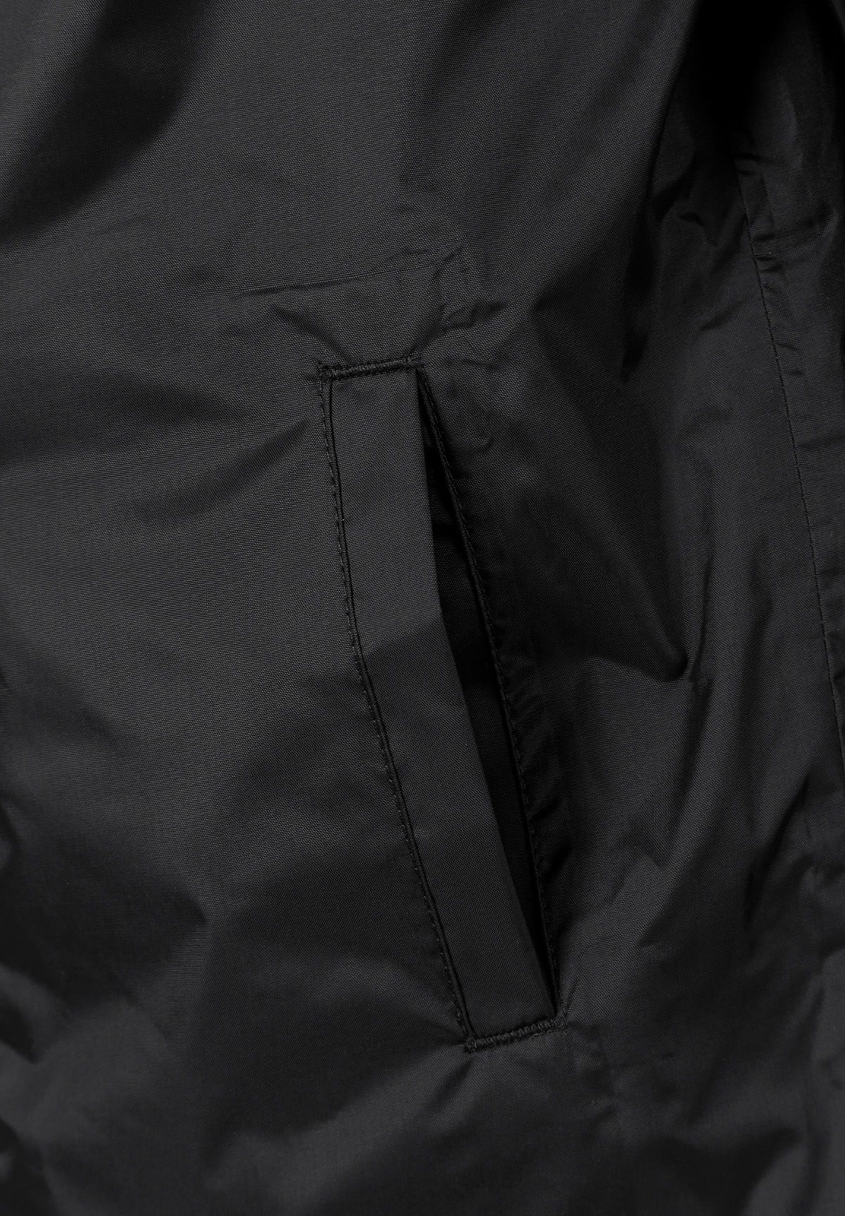 Close-up of the pocket on the black packaway hooded jacket.