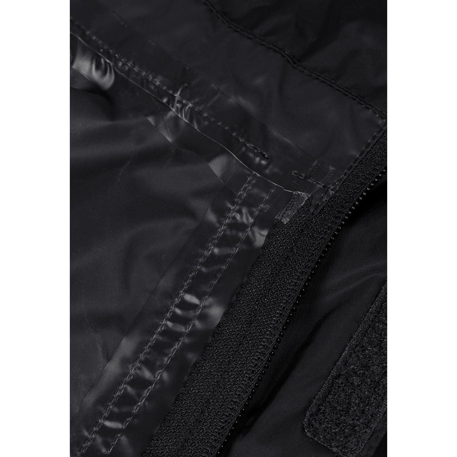 Close-up detail of black waterproof jacket interior showing taped seams and zip construction for weather protection