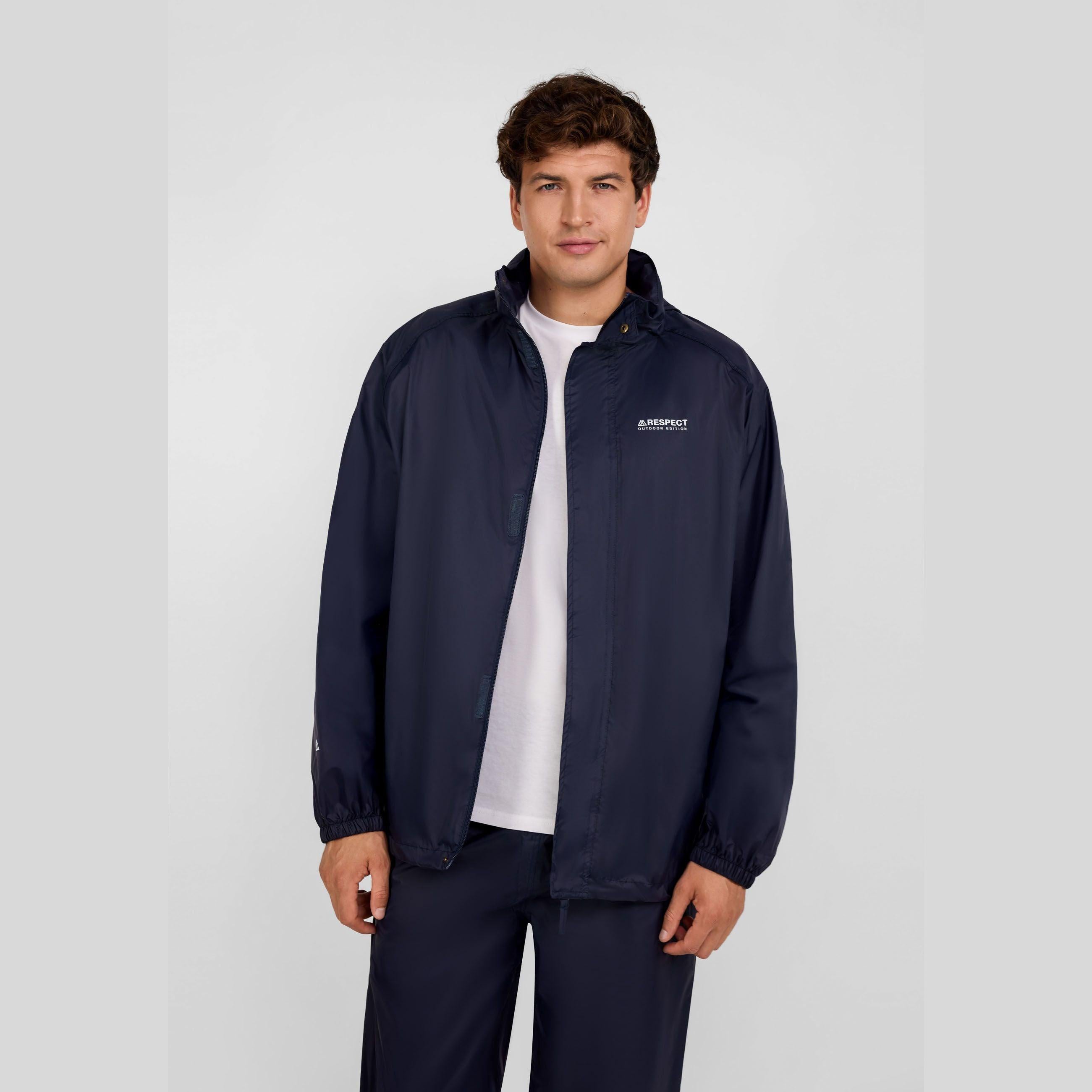 Man in navy packaway waterproof jacket with zip pockets, packaway hood, and chest logo.