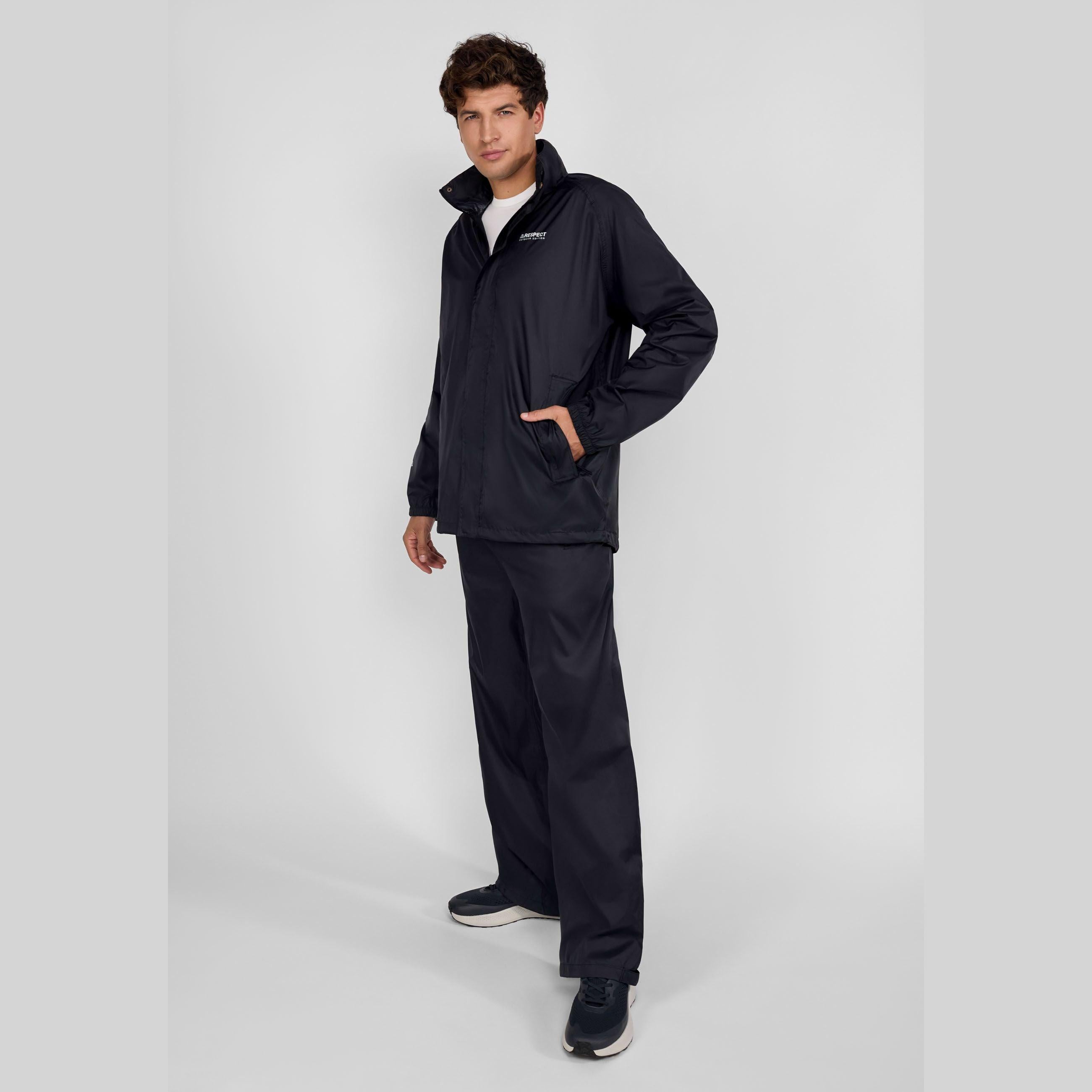 Close-up detail of black waterproof overpants showing side pocket with button closure and adjustable hem with snap fastener