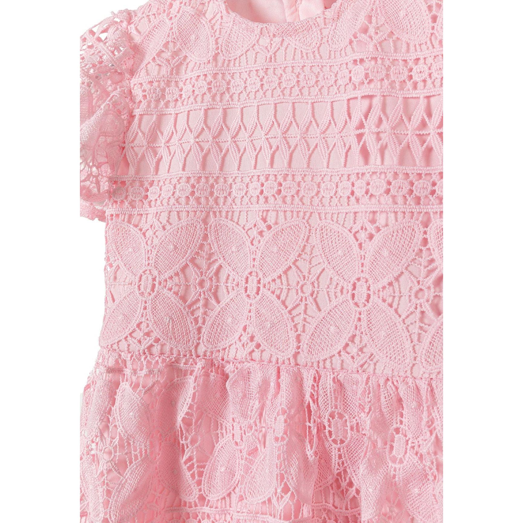 Close-up detail of pink lace fabric showing intricate circular patterns, geometric designs and delicate texture