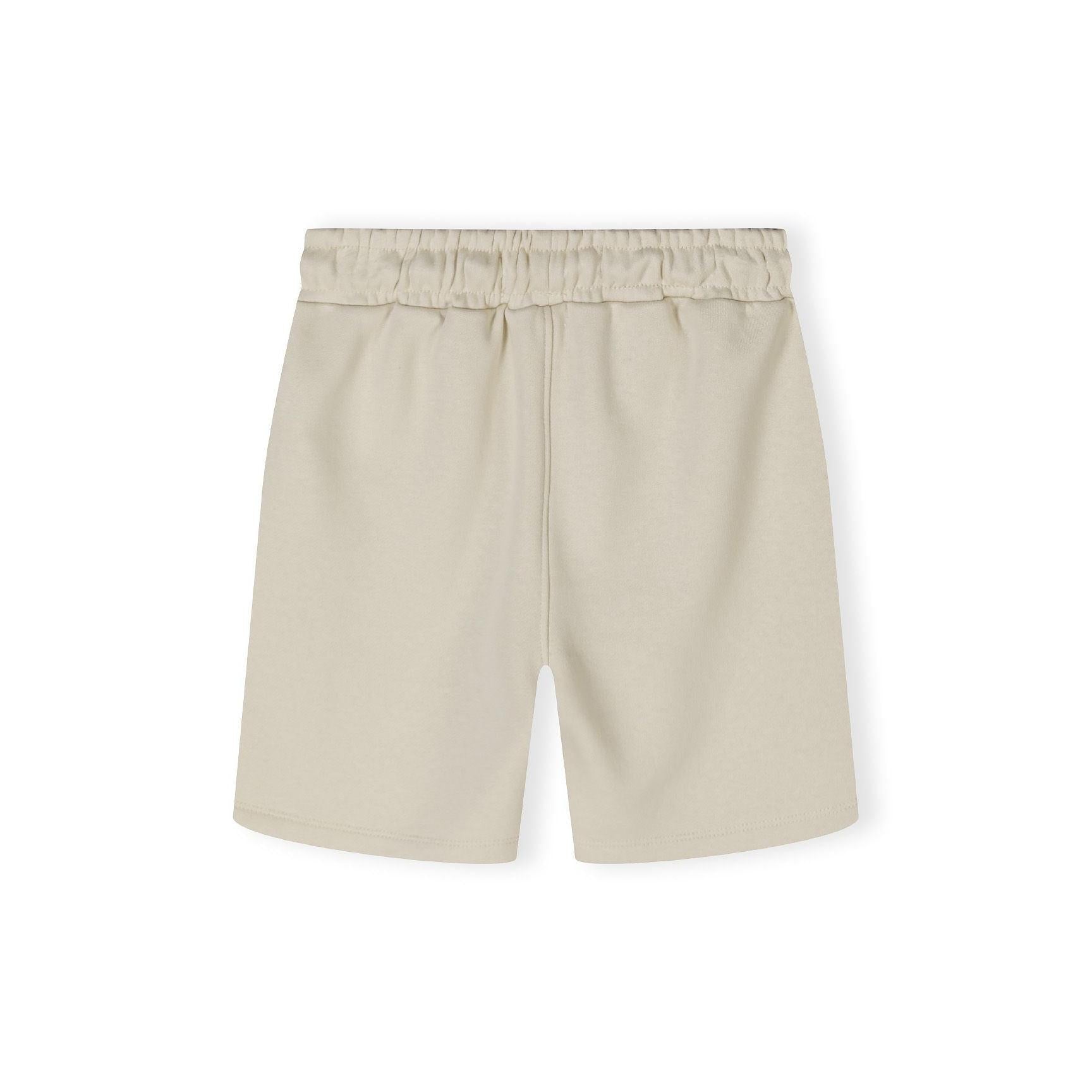 Close-up detail of beige shorts waistband showing elasticated fabric and black drawstring toggle