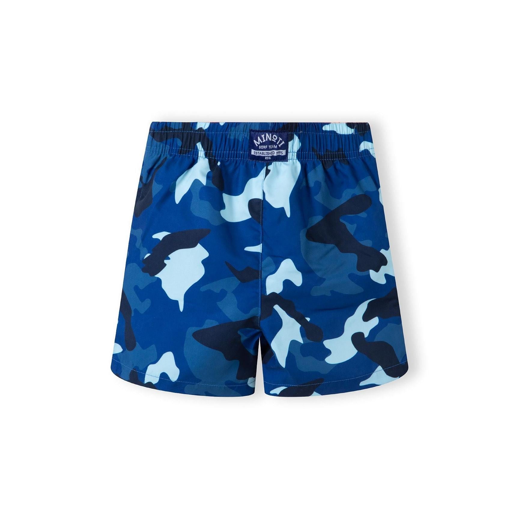 Back view of blue camouflage print swim shorts with elastic waistband showing Minoti brand label on white background