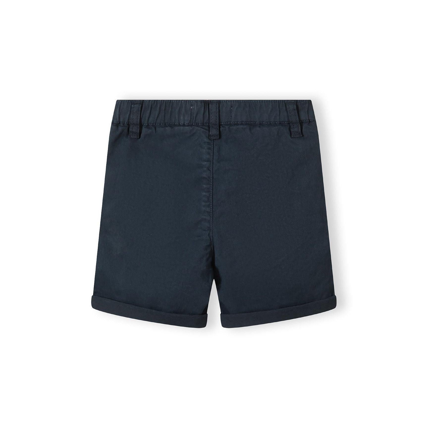 Close-up detail of navy shorts showing adjustable waistband with brown button and pocket construction