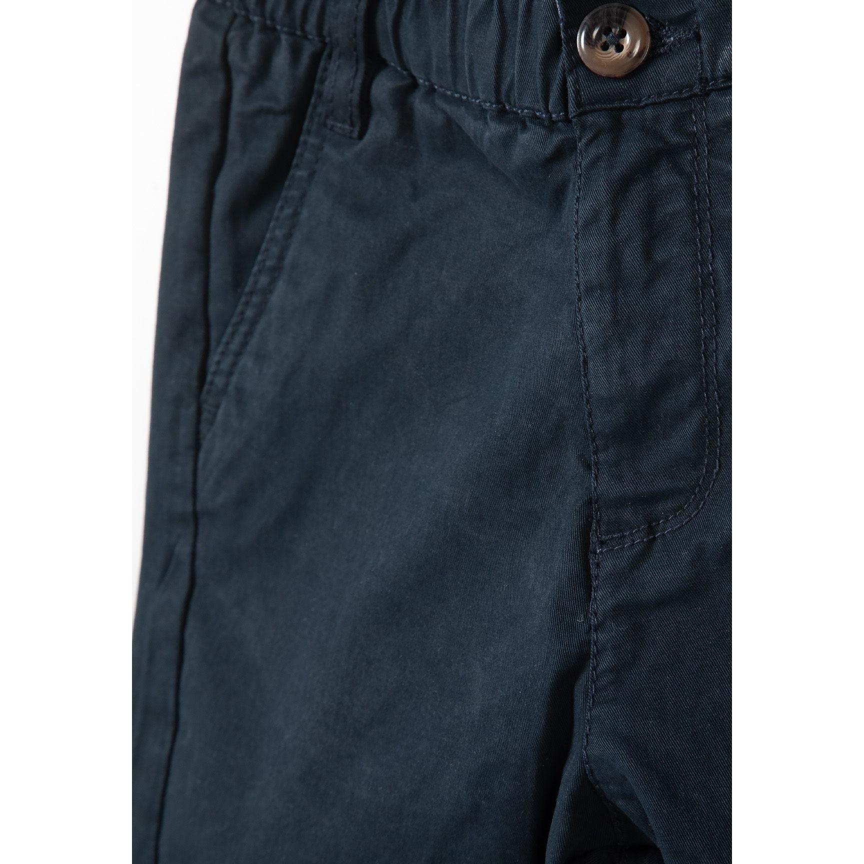 Close-up detail of navy shorts showing adjustable waistband with brown button and pocket construction