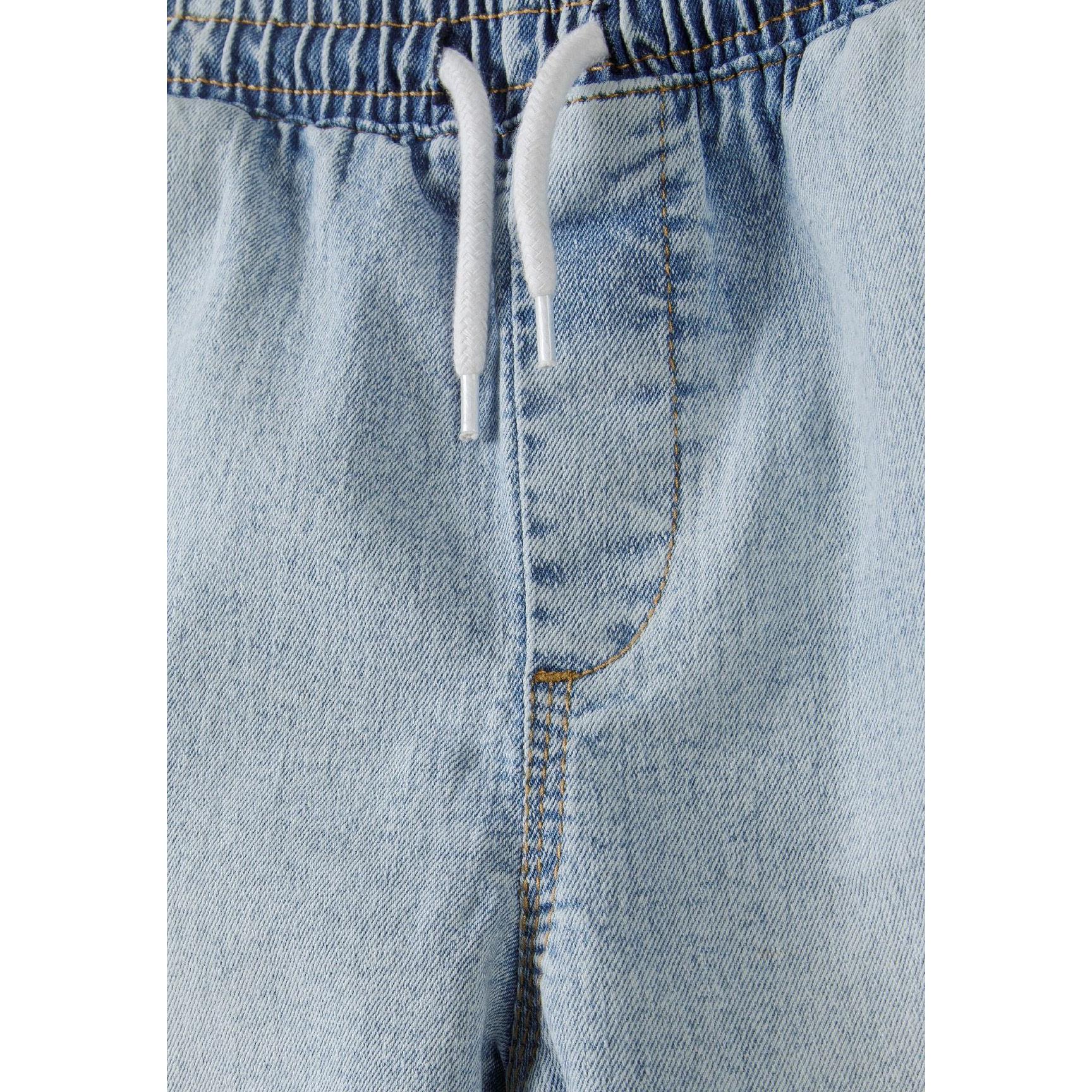 Close-up detail of light blue denim cargo shorts showing elasticated waistband with white drawstring on white background