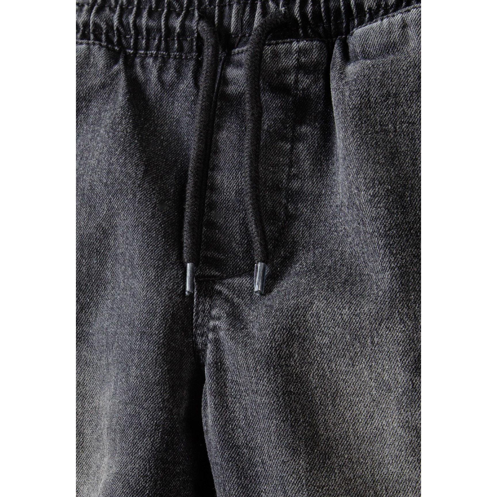 Close-up detail of black denim cargo shorts waistband showing drawcord ties and elastic construction
