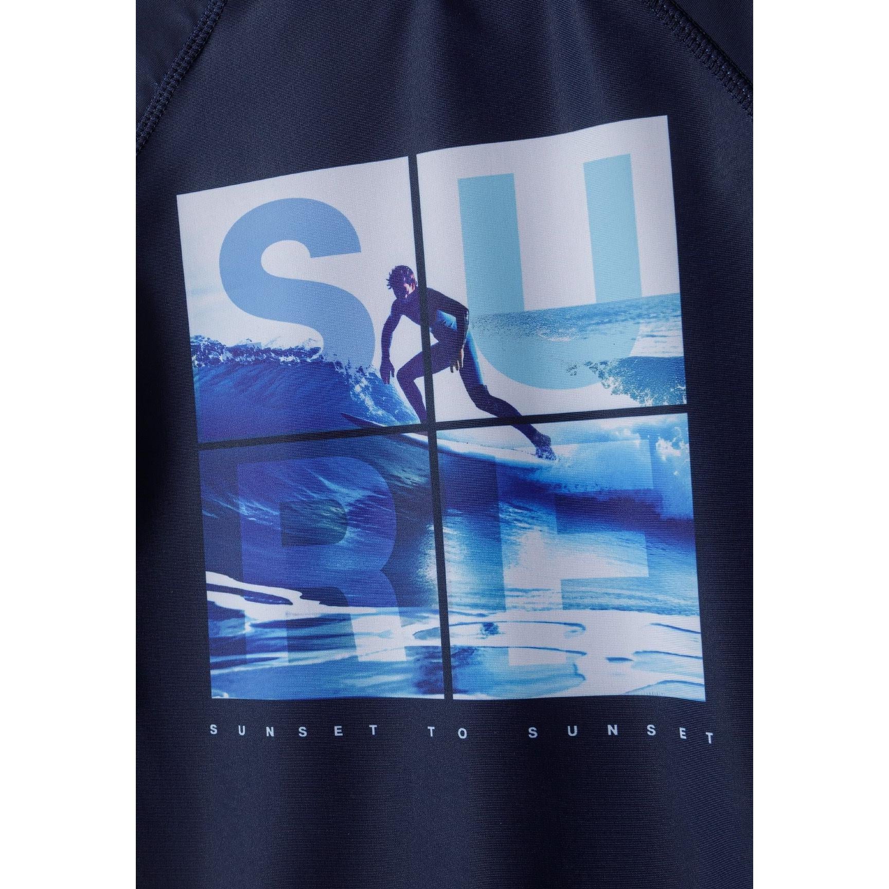 Close-up detail of navy swim top front showing surf print with 'SUN' text overlay on blue water sports scene