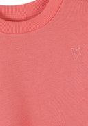 Close-up of coral cotton sweatshirt with ribbed neckline and subtle heart design detail for girls.