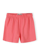 Close-up detail of pink elastic waistband shorts with watermelon heart pattern print, showing Minoti label and fabric texture