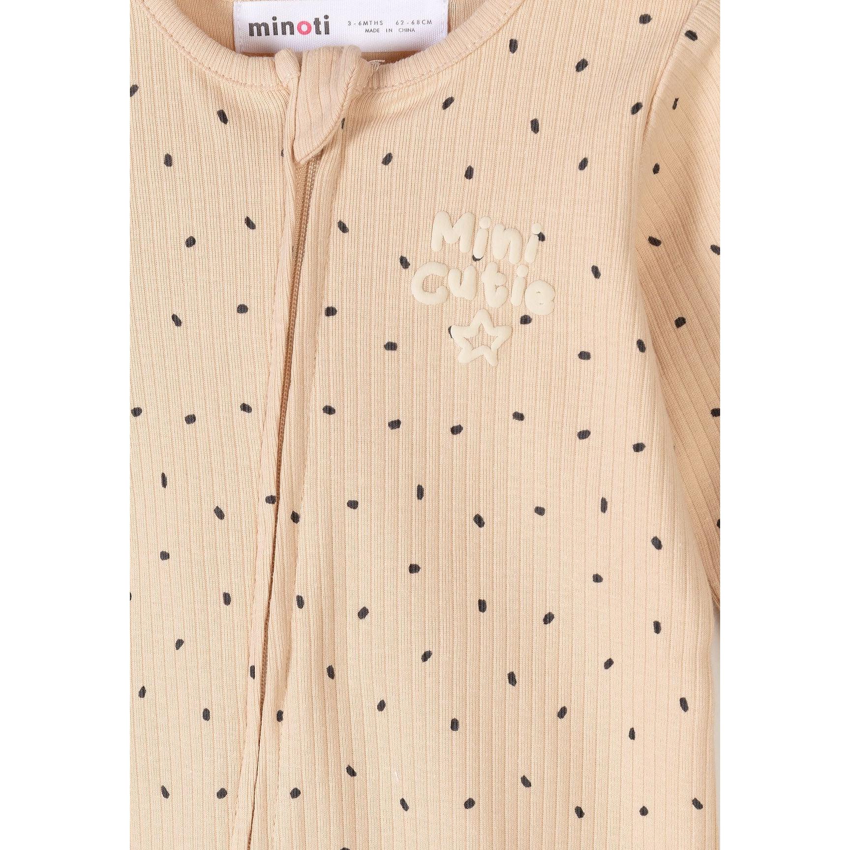 Detail shot of beige polka dot romper showing Mini Cutie text embroidery and black dot pattern on rib knit fabric