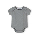 Close-up of beige ribbed bodysuit with black polka dot pattern and Minoti brand label visible at neckline