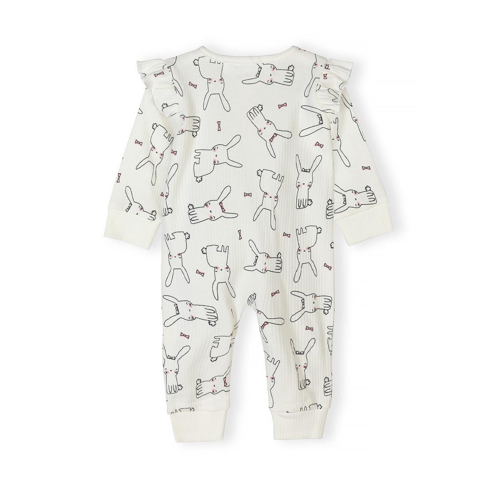Detail shot of cream sleepsuit fabric showing hand-drawn bunny illustrations with pink bow accents and Minoti label