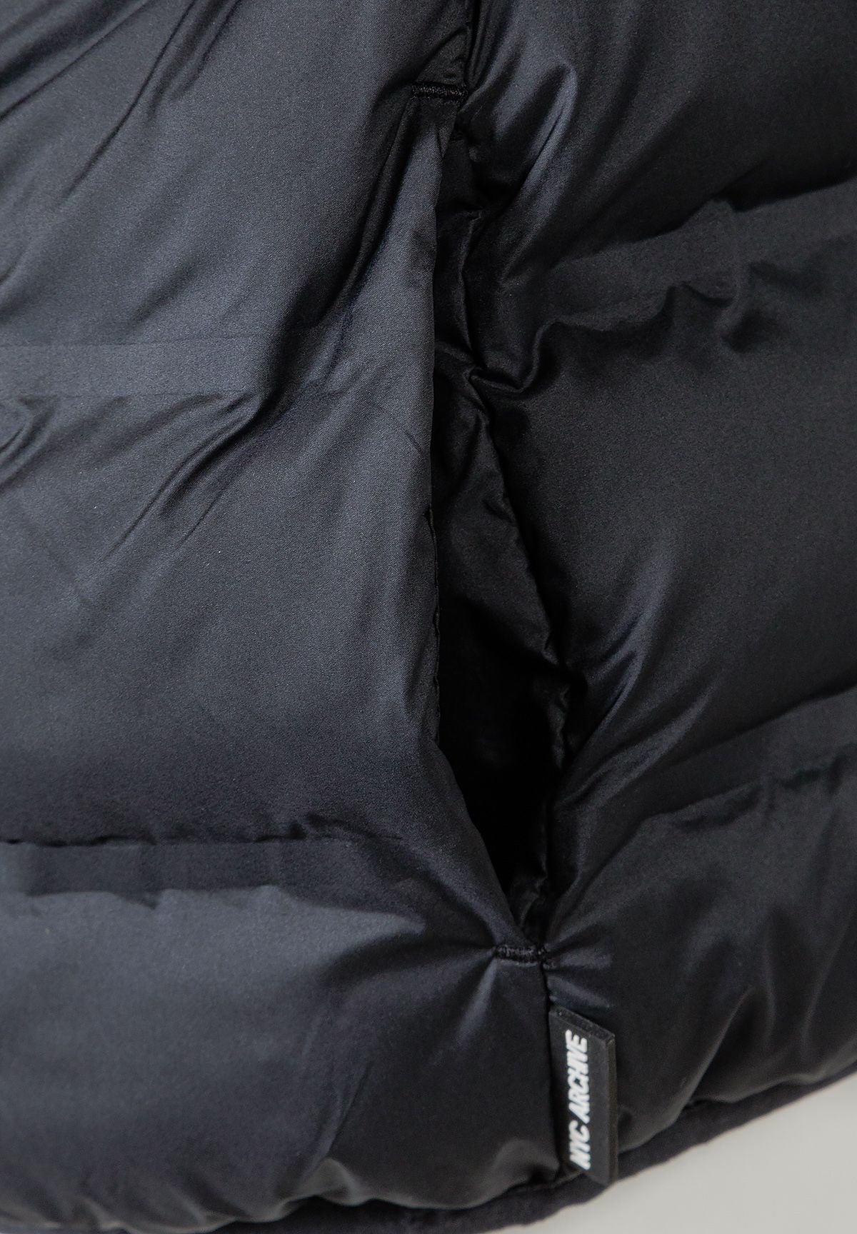 Close-up of the pocket and quilting on the black puffer jacket.