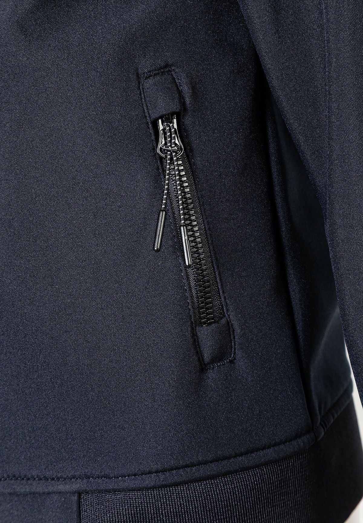 Close-up of the zipped pocket on the black hooded jacket.