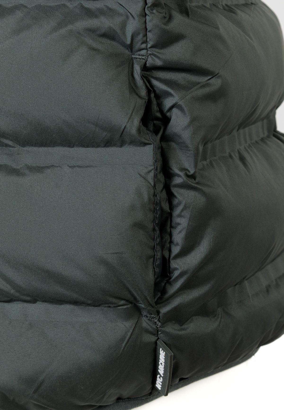 Detail of a boys' quilted sleeveless waistcoat in olive with padded insulation and logo tag.