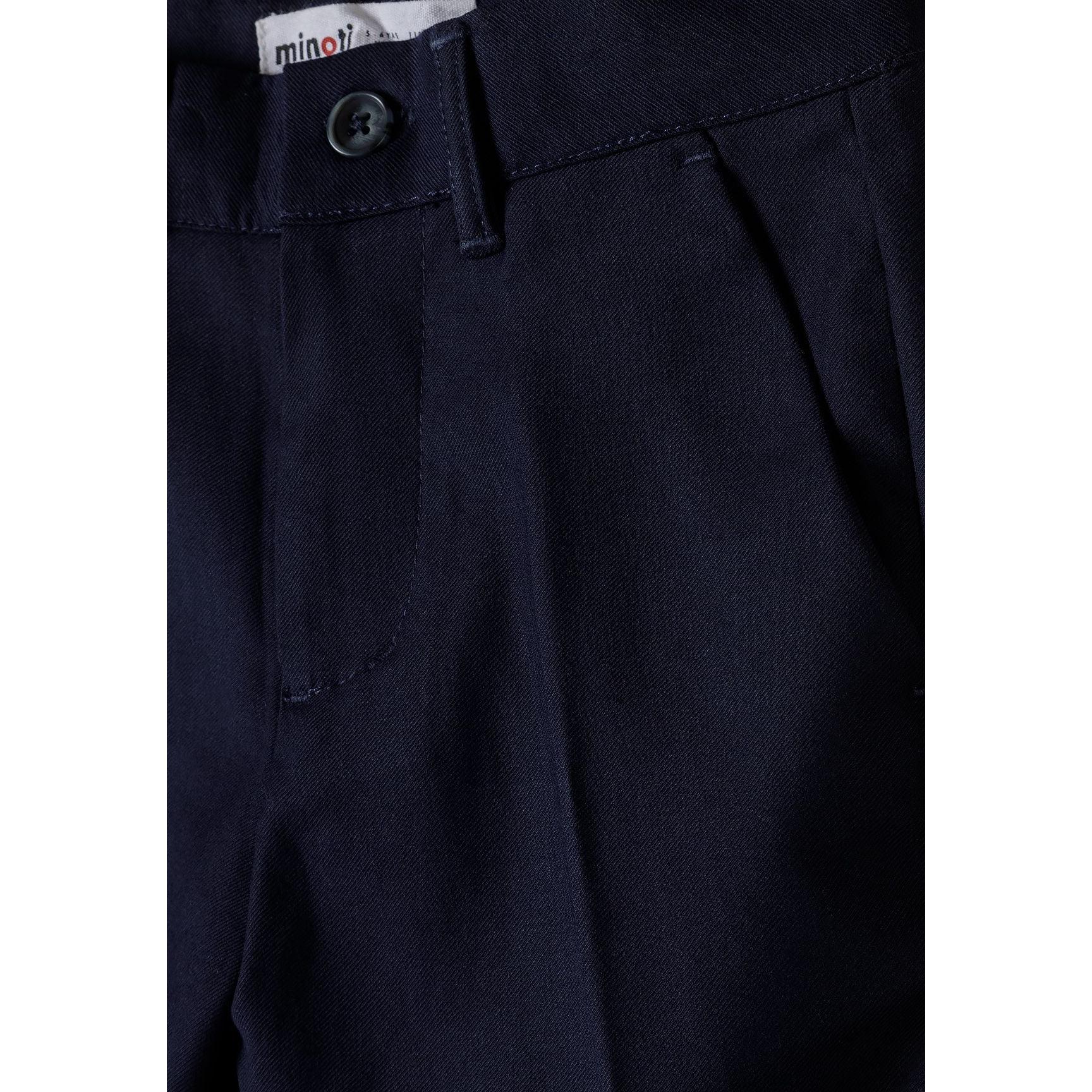 Close-up detail of navy formal trouser waistband showing button closure and Minoti brand label
