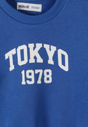 Close-up of blue boys sweatshirt with white Tokyo 1978 print and ribbed neckline design.