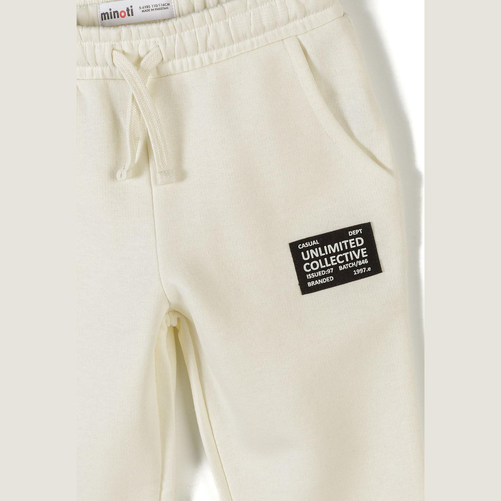 Detail shot of cream hooded sweatshirt showing black branded patch reading 'Unlimited Collective' and black contrast panel on sleeve