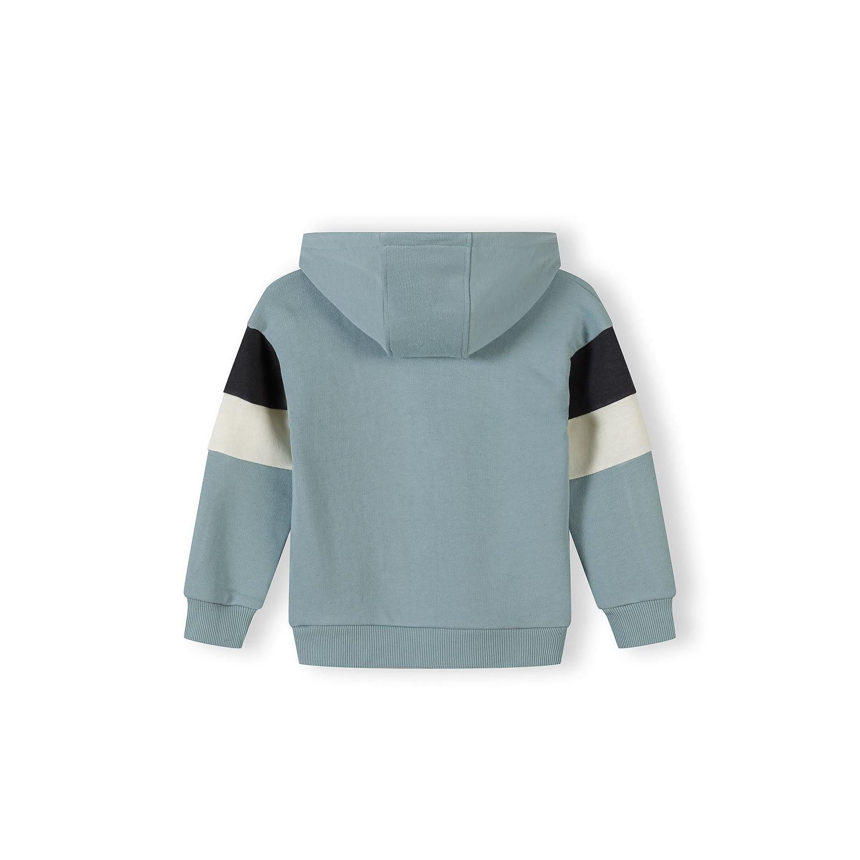 Close-up detail of sage blue jogger waistband and front pocket area showing black rectangular branded patch reading 'Unlimited Collective' with white text