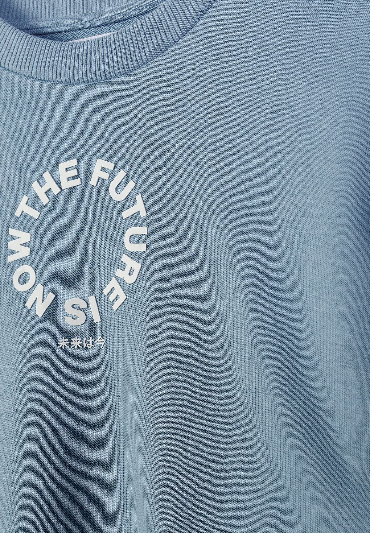 Detail of blue sweatshirt with crew neck and printed text.