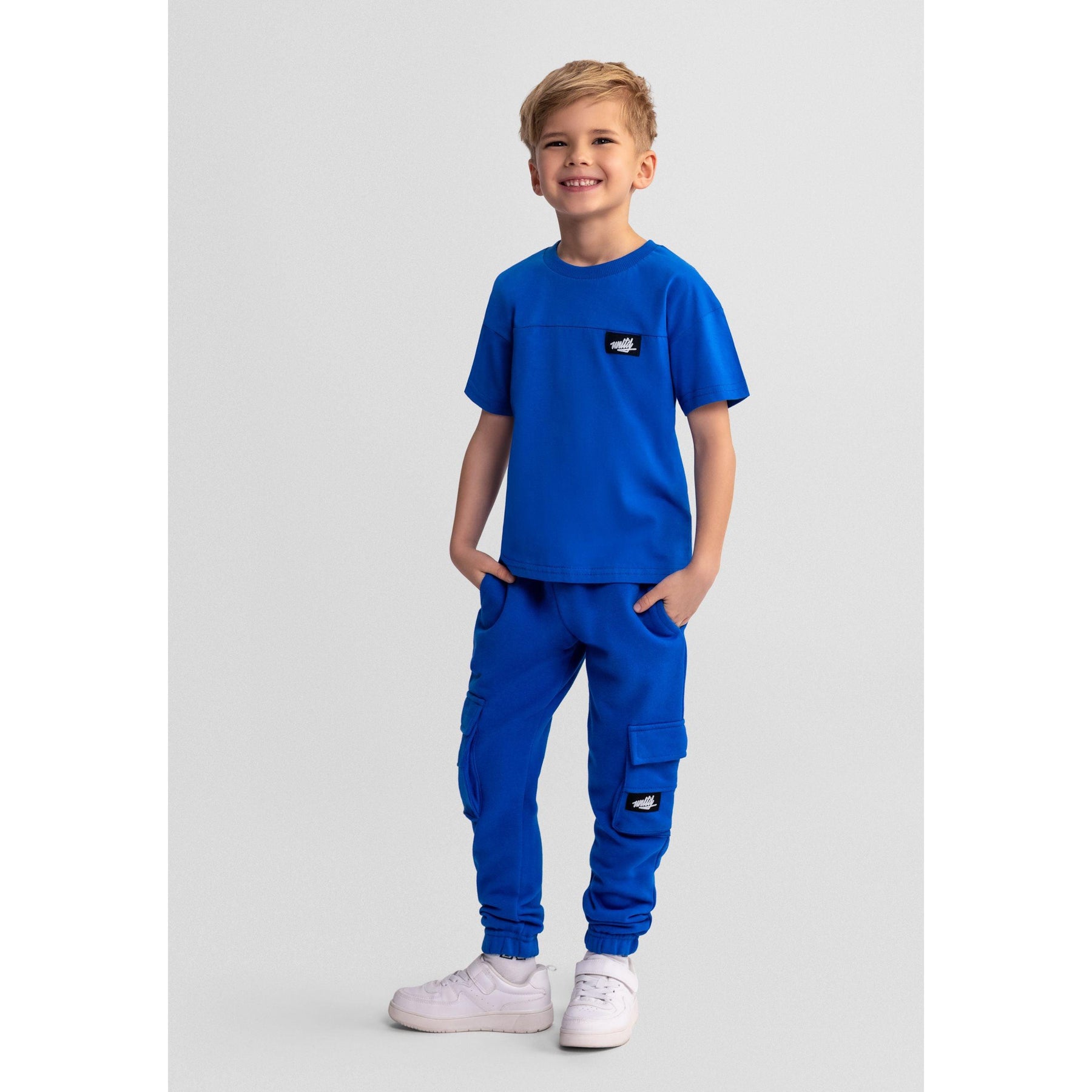 Royal blue cotton t-shirt laid flat showing crew neck design and black Minoti logo patch on chest