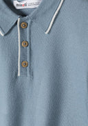 Close-up of a light blue knitted polo shirt with three buttons and a collar.