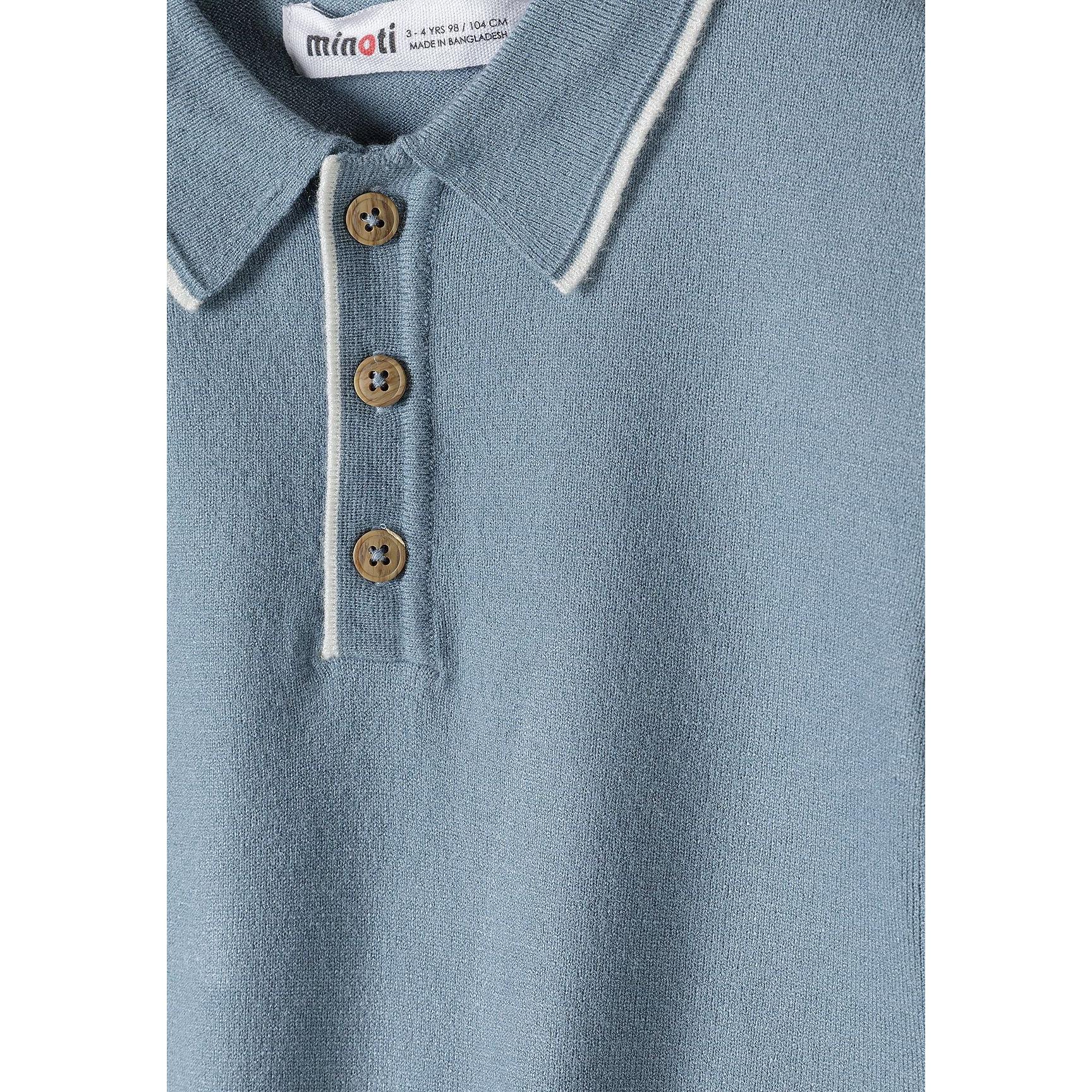 Close-up detail of light blue knitted polo shirt showing Minoti label, three wooden buttons on placket and white collar trim