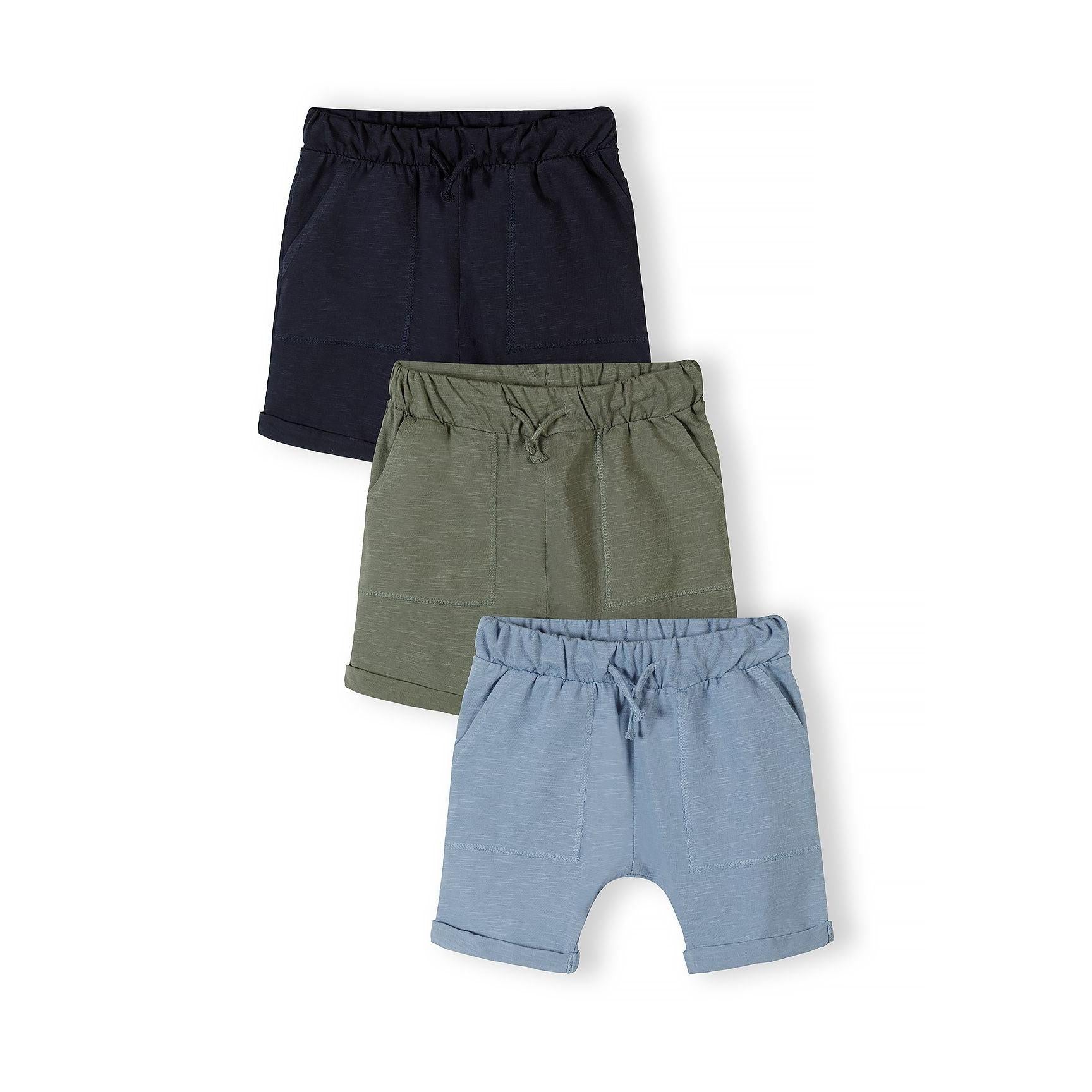 Three pairs of cotton jersey shorts in navy blue, khaki green and light blue arranged in an overlapping stack against white background