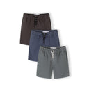 Three woven cotton shorts in grey, blue and navy laid flat showing elasticated waistbands with drawstring ties on white background