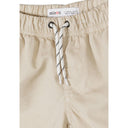 Close-up detail of beige shorts waistband showing Minoti label, elastic gathering, rope drawstring with aglets and front pocket on white background
