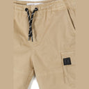 Close-up detail of beige cargo shorts showing drawstring waist with black and white striped cord and cargo pocket with dark label