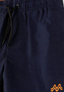 Close-up of navy boys swimming shorts with elasticated waistband, drawstring, and subtle orange wave design detail.