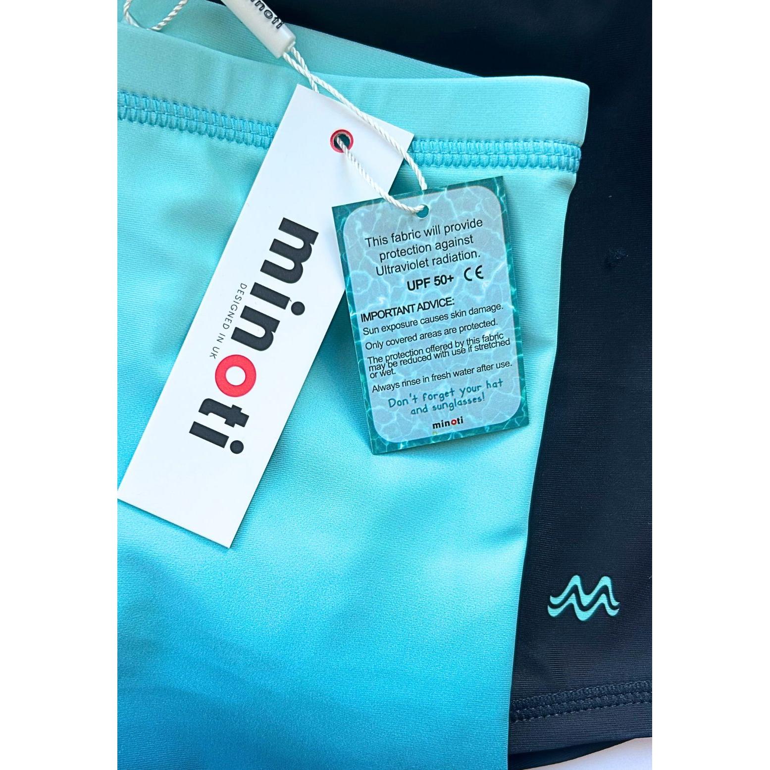 Product label and tag attached to blue gradient swim shorts showing Minoti branding and UPF 50+ fabric protection information
