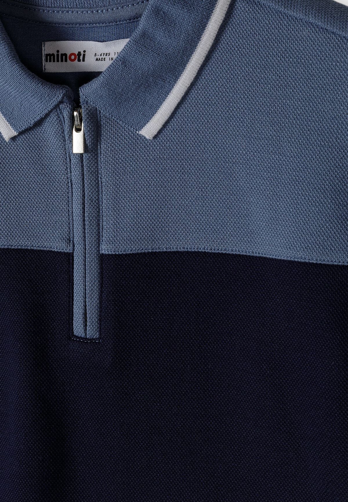 Detail of a boys' navy blue polo shirt with a zip-up collar and textured fabric.