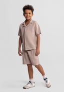 Boys cotton polo shirt and shorts set in muted sand, front view, featuring a classic collar and button placket.