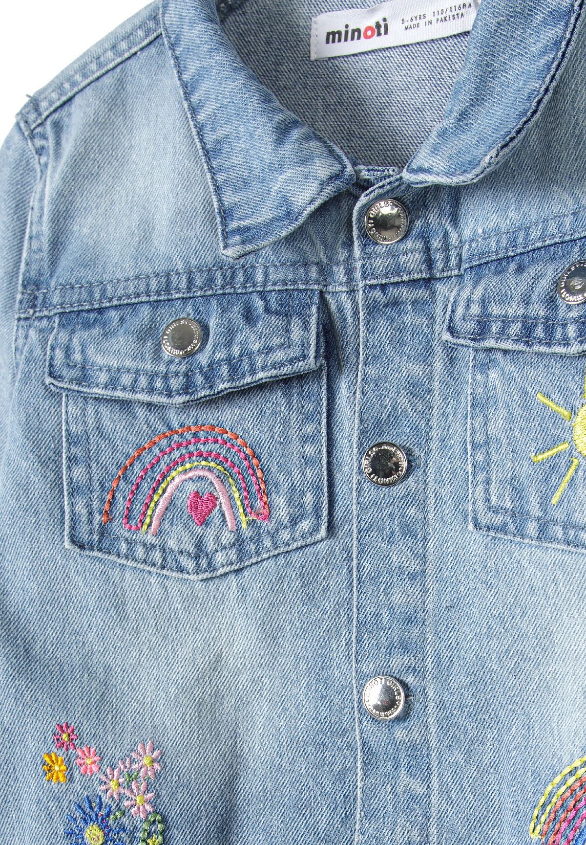 Close-up of the embroidery and fastening on the light blue denim jacket.