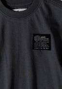 Detail of a grey boys' t-shirt featuring a crew neckline and logo badge.