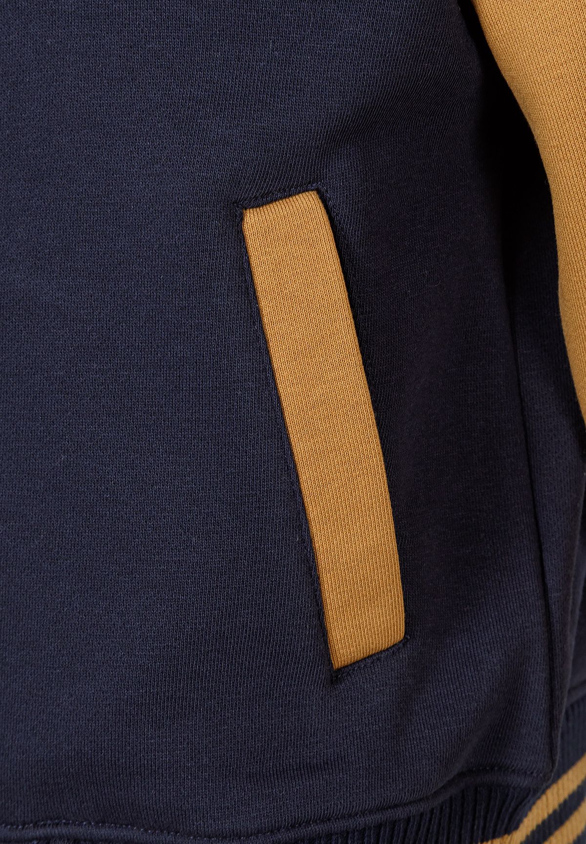 Close-up of a navy baseball jacket with contrasting yellow pocket.