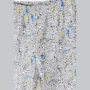 Detail shot of grey shorts with colorful splatter pattern featuring blue, yellow, purple and black paint splashes on light grey fabric