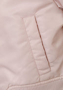 Detail of a girls' lightweight pink bomber jacket showing a side pocket.