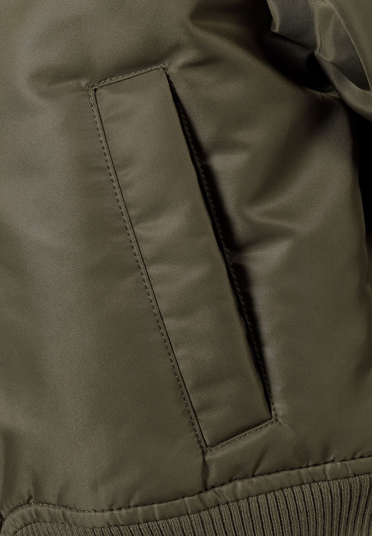 Close-up of the pocket on the khaki bomber jacket.