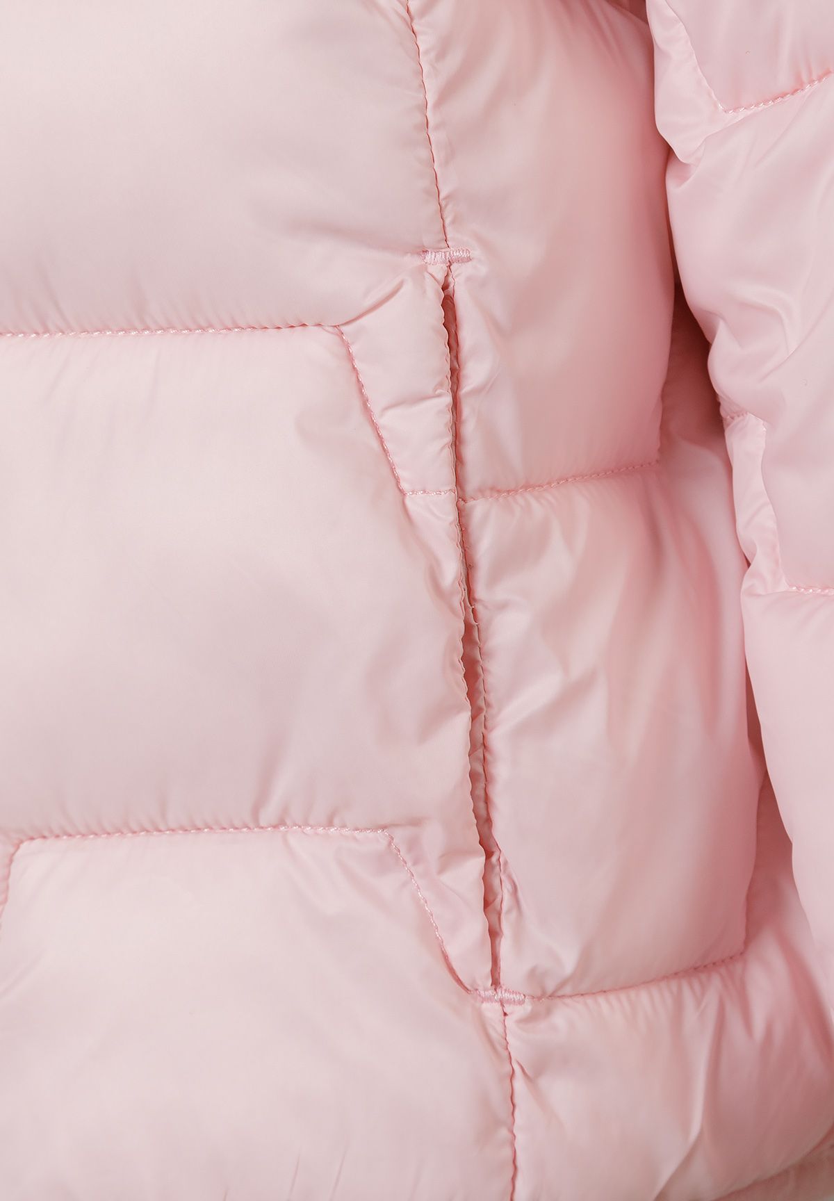 Close-up of the pocket and quilting on the light pink puffer jacket.