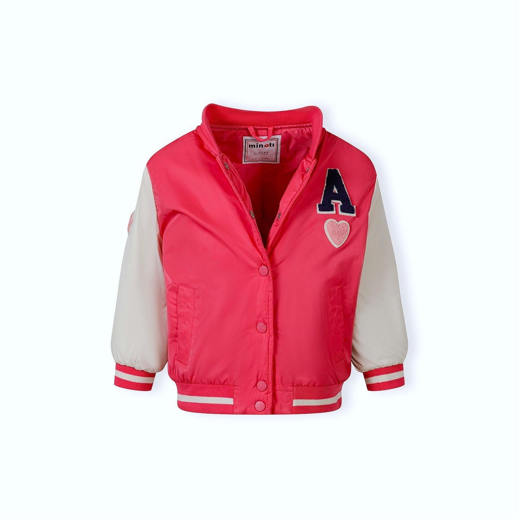 Front view of girl in pink varsity bomber jacket with letter A patch, navy tulle skirt and red sneakers on white background