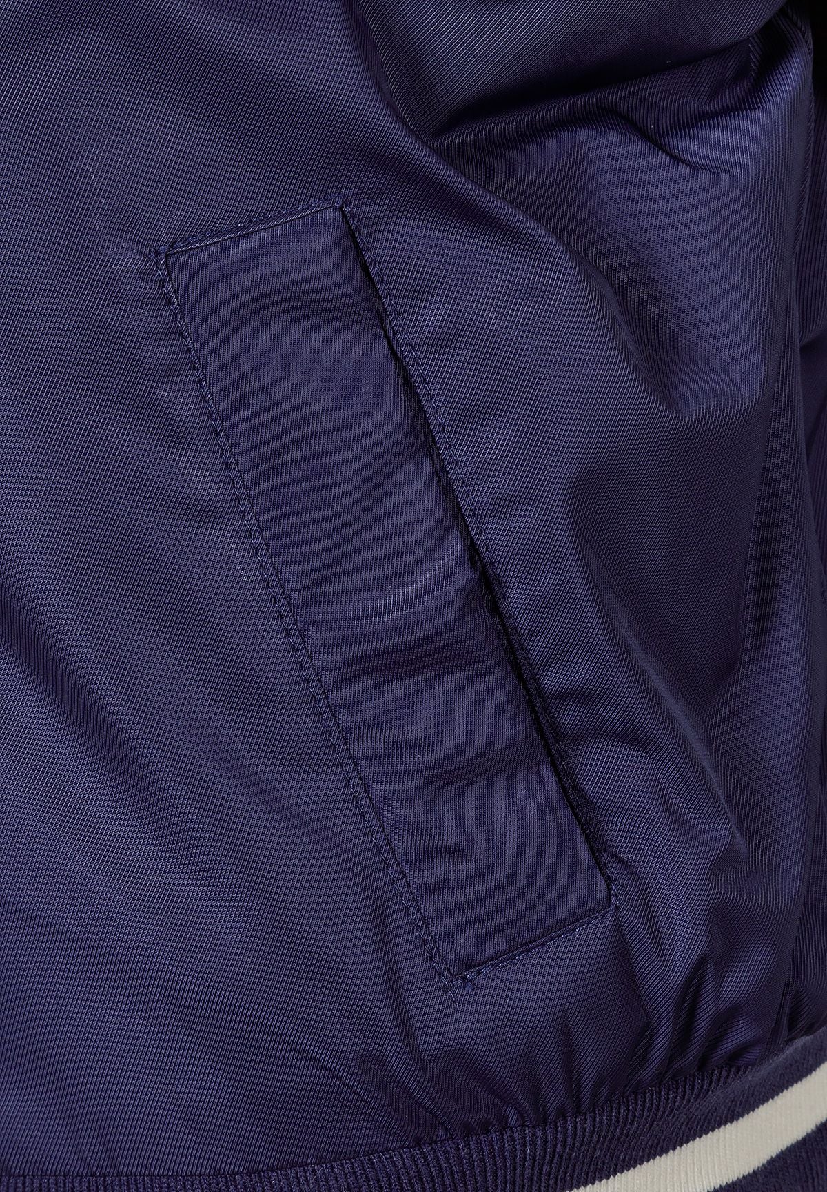 Close-up of the pocket on the navy varsity jacket.