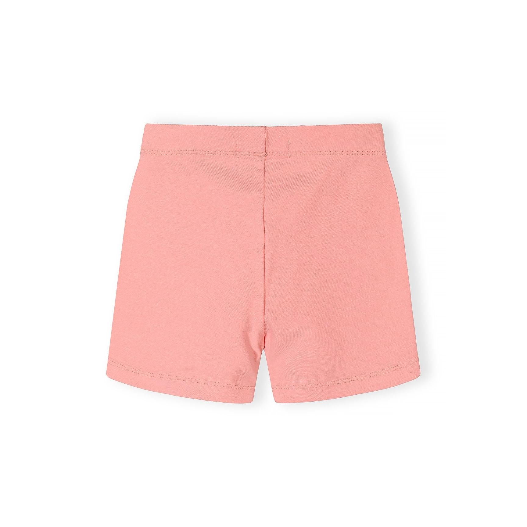 Close-up detail of coral pink cycle shorts showing Minoti brand label inside waistband and soft cotton stretch fabric texture