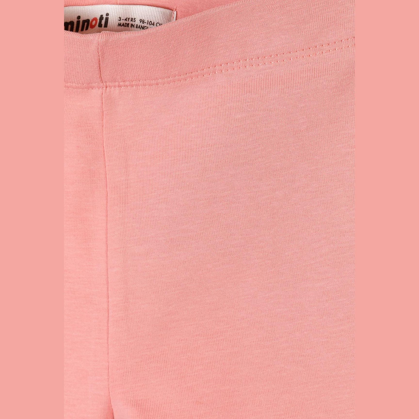 Close-up detail of coral pink cycle shorts showing Minoti brand label inside waistband and soft cotton stretch fabric texture