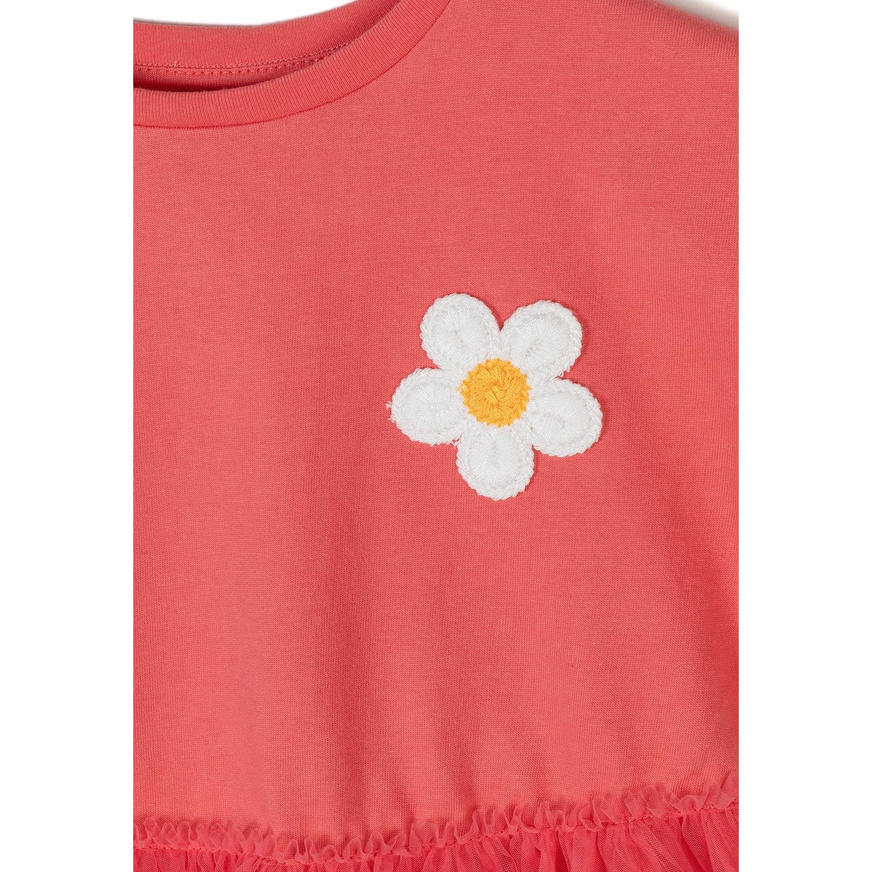 Close-up detail of white daisy flower embroidery on coral cotton jersey fabric showing stitching and fabric texture